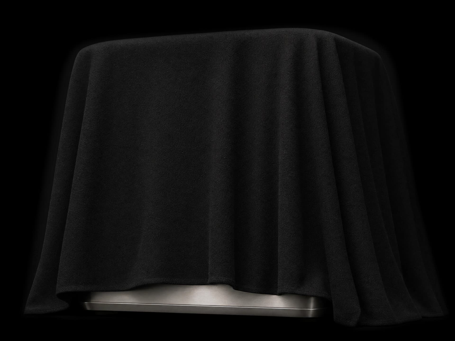 Matte black drape revealing a warm silver machine base.